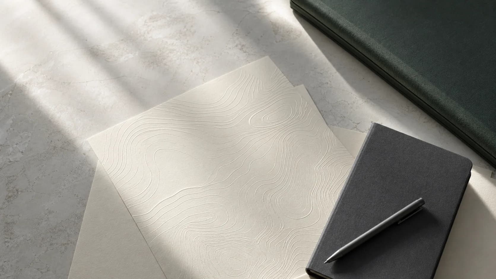 Layered topographic papers and an investment notebook in natural light